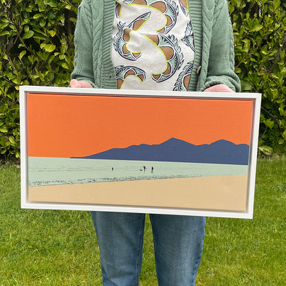 Landscape-oriented fine art canvas print titled Let's Go to the Beach by Norma Slack, showing a family and dog silhouetted against the Mourne Mountains and an orange sky.